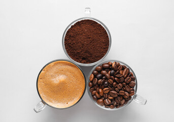 Cups of hot espresso and coffee beans on white background