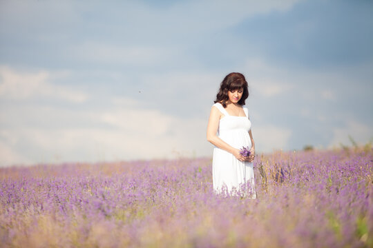 a pregnant woman in a field of flowers of lavender purple color