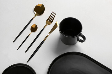 Clean plates, cup and golden cutlery on grey table