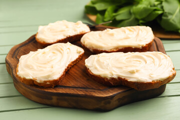 Obraz na płótnie Canvas Wooden board of tasty sandwiches with cream cheese on green wooden background