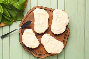 Wooden board of tasty sandwiches with cream cheese on green wooden background