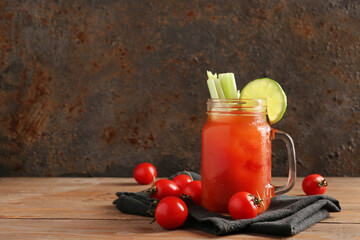 Mason jar of bloody mary with celery and lime on wooden table