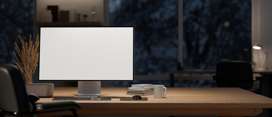 A computer mockup and decor on a wooden table in a modern dark office room at night.