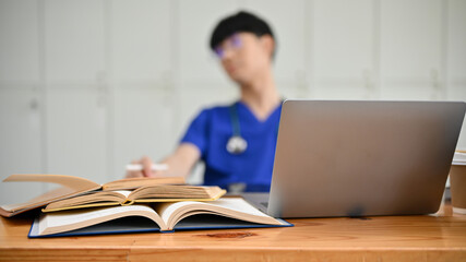 Selective focus, Medical books and a laptop on a wooden table over blued background