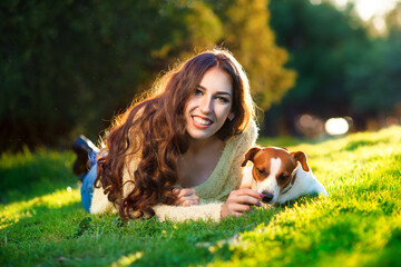 Happy young woman hugging and having fun with her Jack Russell Terrier In the blooming garden