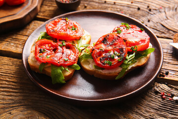 Plate of sandwiches with tasty grilled tomatoes and arugula on wooden background