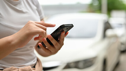 Close-up image of a female using her smartphone while walking along the parking lot.