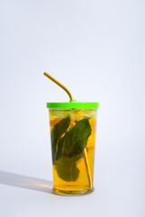 Glass of ice tea with mint and lemon on white background