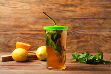 Glass of ice tea with mint and lemon on wooden background
