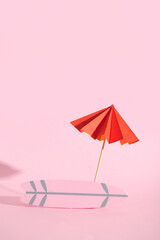 Mini surfboard with umbrella on pink background