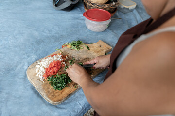 An adult Hispanic woman is cutting coriander to make a traditional salad