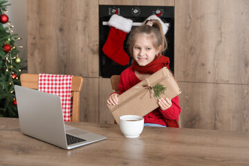 Cute little girl with Christmas gift in kitchen