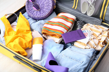 Suitcase with clothes, beach accessories, passport and ticket on floor. Travel concept