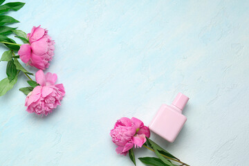 Composition with bottle of perfume and beautiful peony flowers on light blue background