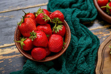 Bowl with fresh strawberries on black wooden background