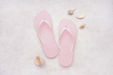 Pink flip-flops with shells on white grunge background