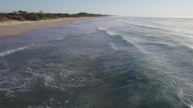 Foamy Waves Coming To The Coolum Beach Sandy Shoreline During Sunrise In QLD, Australia. - aerial
