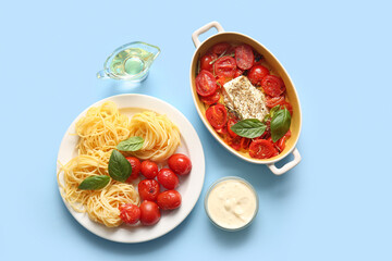 Baking dish with tasty tomatoes, feta cheese and pasta on blue background