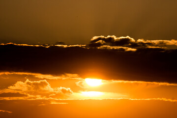 Bright orange sun peeking out from behind dark clouds