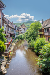 Fototapeta na wymiar A picturesque colorful view of half-timber buildings at a small creek in the village of Kaysersberg in Vosces region.