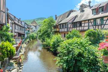Fototapeta na wymiar A picturesque colorful view of half-timber buildings at a small creek in the village of Kaysersberg in Vosces region.