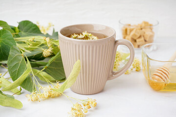 Cup of linden tea and bowl with honey on white table