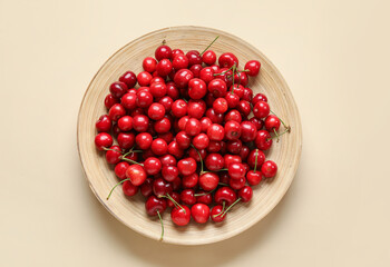 Plate with sweet cherries on beige background