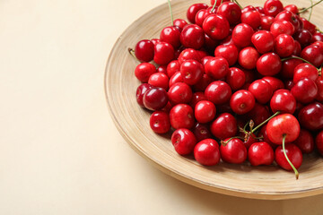 Plate with sweet cherries on beige background