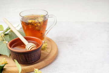 Bowl with linden honey and glass cup of tea on white background