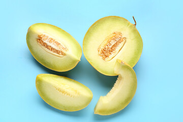 Half of sweet melon with pieces on blue background