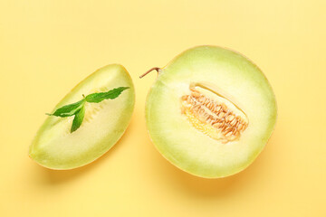 Half of sweet melon with piece and mint on yellow background