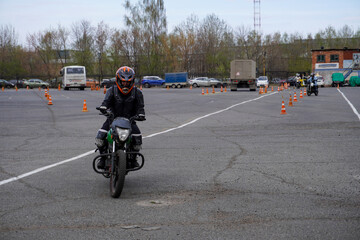 A young woman is learning to ride a motorbike in a motorcycle school. She is taught by a teacher