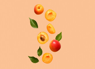 Flying fresh apricots with pieces and leaves on orange background
