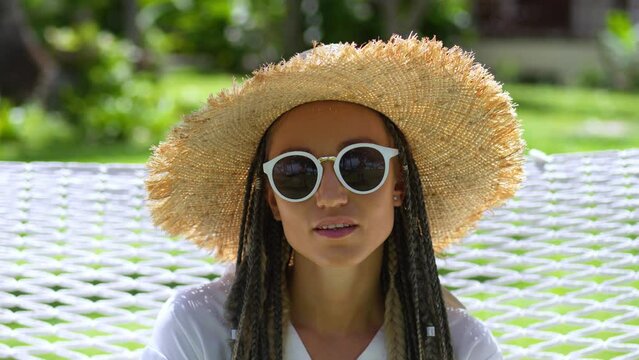 Portrait of attractive woman traveler in straw hat and sunglasses enjoying summer holidays at tropical island. Woman in straw hat enjoying summer weather outdoors while holidays. Concept of travel.