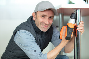man using hand drill to assemble a table