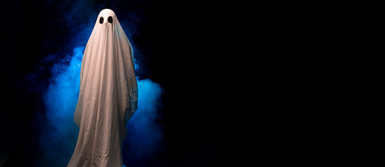 Scary ghost covered in sheet on a dark background in the smoke. Halloween poster.