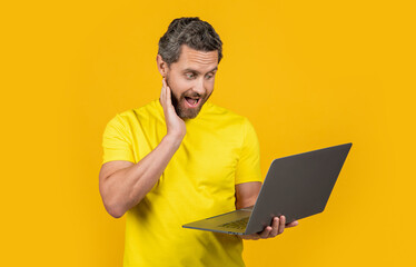 image of surprised man programmer with laptop. man programmer isolated on yellow.