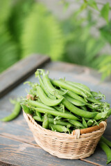 green peas in a wicker basket on a rustic background