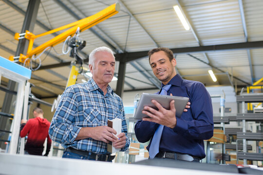 industrial manager holding tablet showing information to colleague
