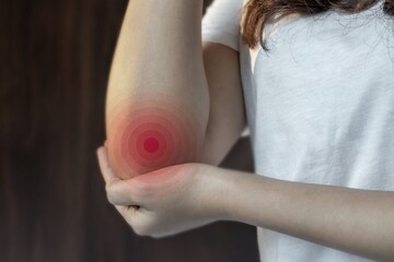 Pain in the elbow joint of Asian young woman.