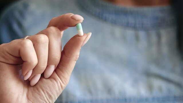 Unrecognizable female hand capsule pill medical drug for headache virus illness cure aid therapy
