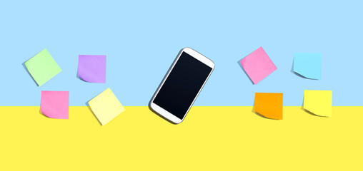 Smartphone with many colorful sticky notes - desk flat lay