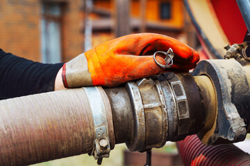 a hand connects a suction hose to a sewage tanker truck. Sewer pumping machine. Septic truck. Pumping wastewater from a septic tank. Septic tank maintenance - obrazy, fototapety, plakaty