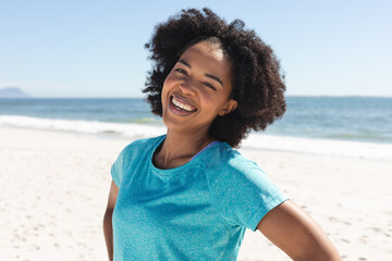 Portrait of happy african american woman looking at camera and smiling on sunny beach