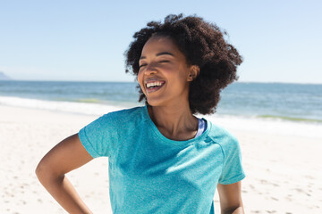 Portrait of happy african american woman looking at camera and smiling on sunny beach