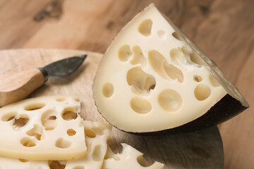 Emmental cheese triangle, Swiss cheese, on wooden board whith knife and craft bag. High resolution image
