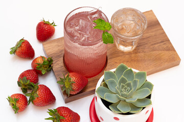 strawberry juice in a glass on a wooden plate with strawberries on the side