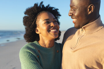 Happy african american couple embracing on sunny beach by the sea