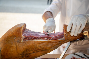 Knife cutting serrano chef man hand slicing of italian dry cured pork cured ham prosciutto - obrazy, fototapety, plakaty