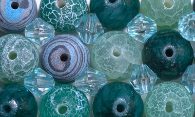 Niebiesko turkusowo zielona tapeta stworzona z barwnych, wzorzystych koralików do nawlekania,...